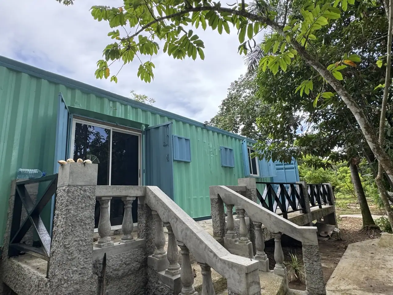 River’s Edge green cabin with exterior steps, balcony and trees